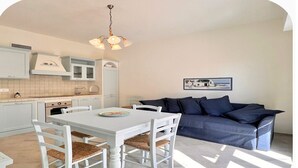 Une cuisine moderne avec des meubles blancs, une table à manger avec des chaises et un canapé bleu.