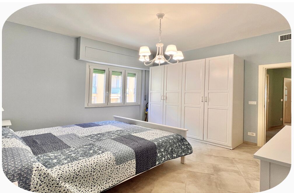 Un dormitorio con cama, candelabro, armario y ventana con persianas.
