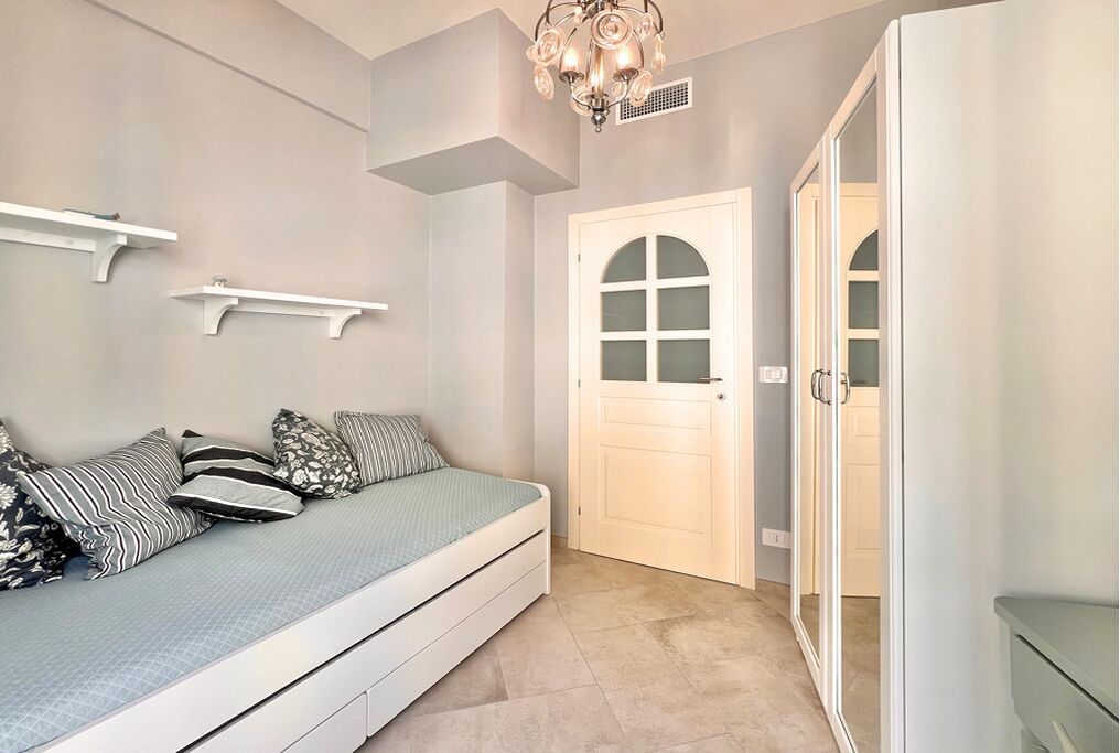 Une chambre à coucher comprenant un lit, une armoire, une porte à panneaux de verre et un lustre.