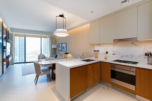 A modern kitchen with a central island, built-in oven, and a large window offering a city view. - 2BR Address Dubai Opera | Walk to Mall, Burj Khalifa & Opera (Dubai)