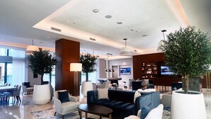 Un hall d’hôtel moderne avec un espace salon, un coin repas et une cuisine en arrière-plan.