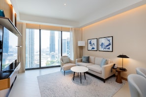 A modern living room with a sofa, armchairs, a coffee table, and a TV. - 2BR Address Dubai Opera | Walk to Mall, Burj Khalifa & Opera (Dubai)