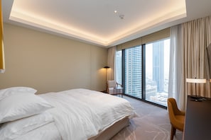 A hotel room with a large bed, a desk, a chair, and a view of the city through large windows. - 2BR Address Dubai Opera | Walk to Mall, Burj Khalifa & Opera (Dubai)