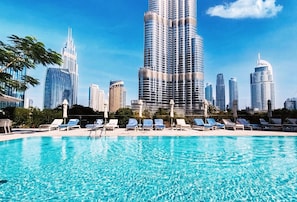 A swimming pool with lounge chairs and a city skyline in the background.