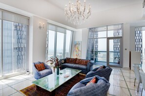 A spacious living room with a glass coffee table, leather sofas, and large windows offering city views.