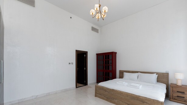 Une chambre spacieuse avec un grand lit, une tête de lit en bois, une table de chevet et une commode rouge.