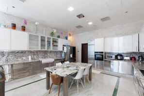 A modern kitchen with marble countertops, stainless steel appliances, and a dining area with a marble table and white chairs.