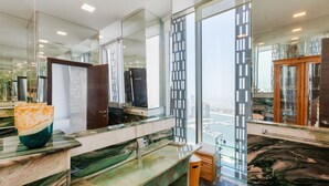 Une salle de bain moderne avec un grand miroir, un comptoir en marbre et une vue sur la ville.