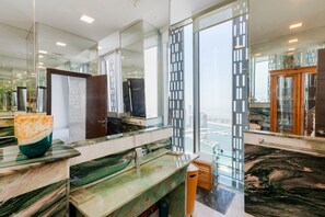 A modern bathroom with a large mirror, a marble countertop, and a view of the city.
