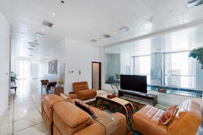 A modern living room with leather sofas, a glass coffee table, a flat-screen TV, and a large window with a view of the city. - Elegant 4BR Marina Penthouse | Private Pool (Dubai)