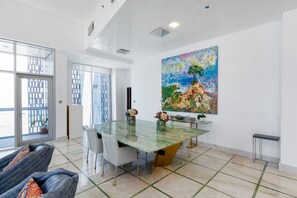 Un comedor amplio con una mesa de vidrio, sillas y un cuadro grande en la pared.