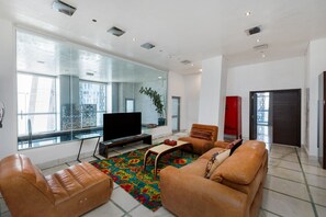 Un soggiorno moderno con divani in pelle, una TV a schermo piatto e un'ampia finestra con vista sulla città.