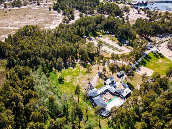 An aerial view of a resort with multiple cabins, a central building with a pool, and a marina.