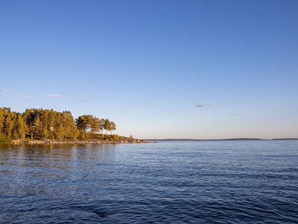 A calm lake with a forested shoreline and distant hills.