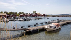 Un port de plaisance avec des bateaux amarrés, des quais en bois et des bâtiments rouges en arrière-plan.