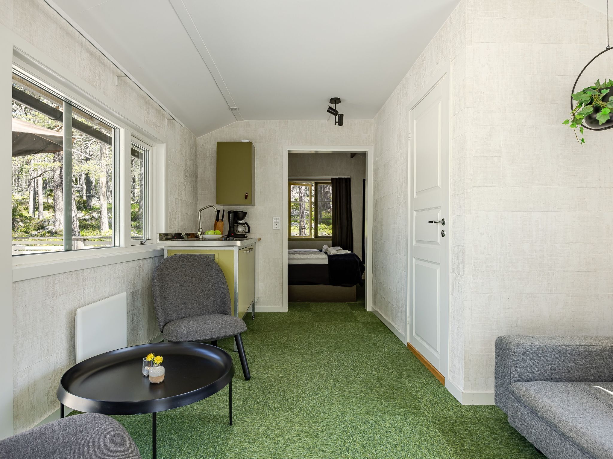 A compact room with a kitchenette, a bed, and a seating area.
