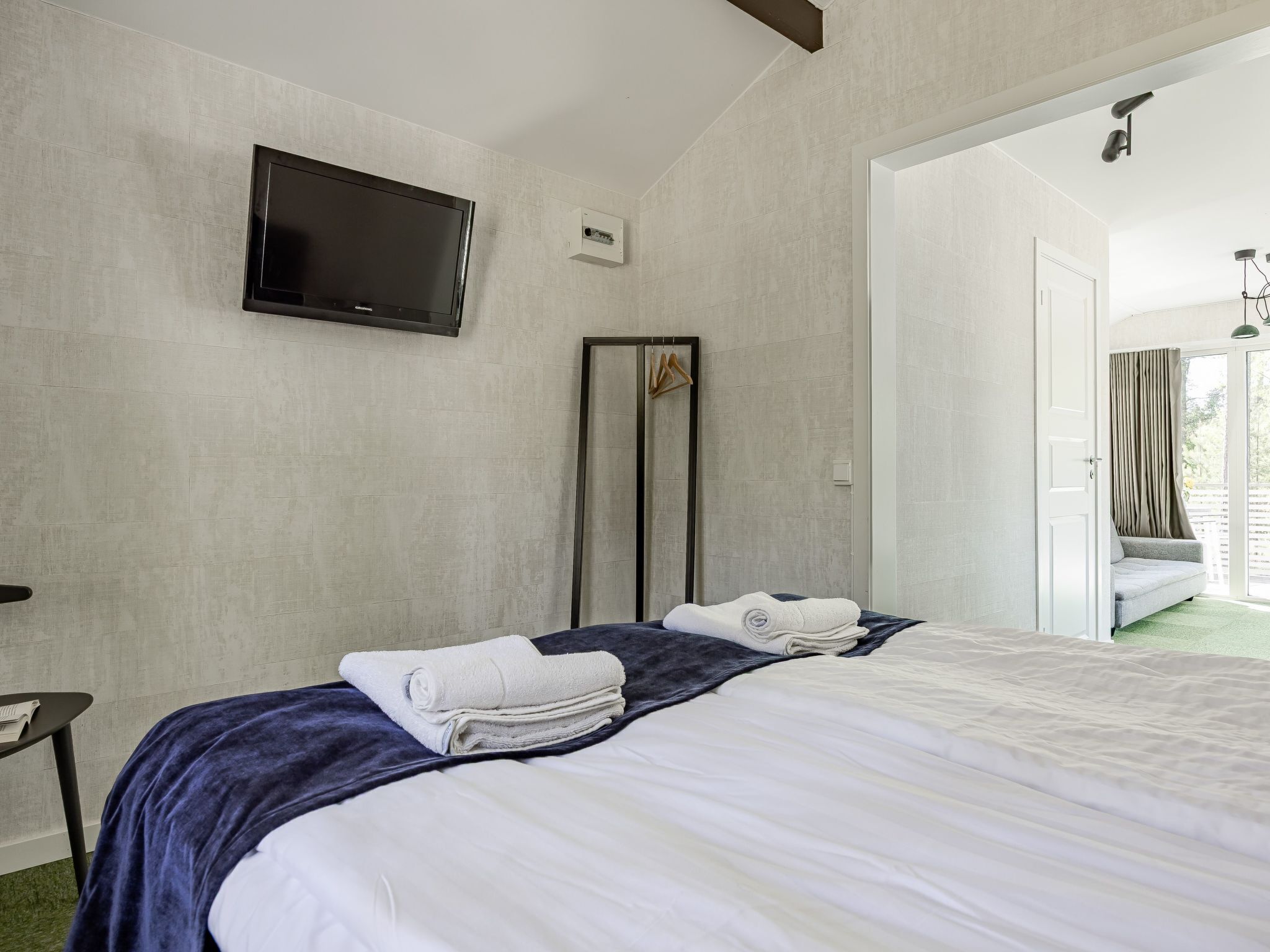 Hotelkamer met een bed, een flatscreen televisie, een spiegel en een deur naar een balkon.