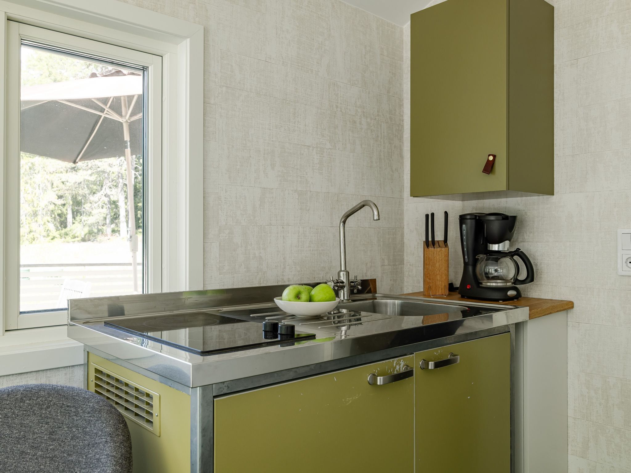 A kitchen with a sink, a coffee maker, and a bowl of apples.