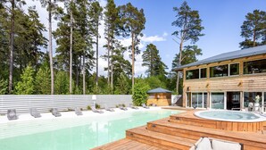 A wooden deck with a hot tub, lounge chairs, and a pool. - Hölick Minichalet Plus 6 by Interhome (Hölick)