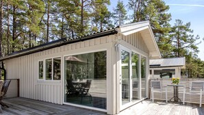 A cabin with a deck, sliding glass doors, and a small patio area. - Hölick Minichalet Plus 6 by Interhome (Hölick)