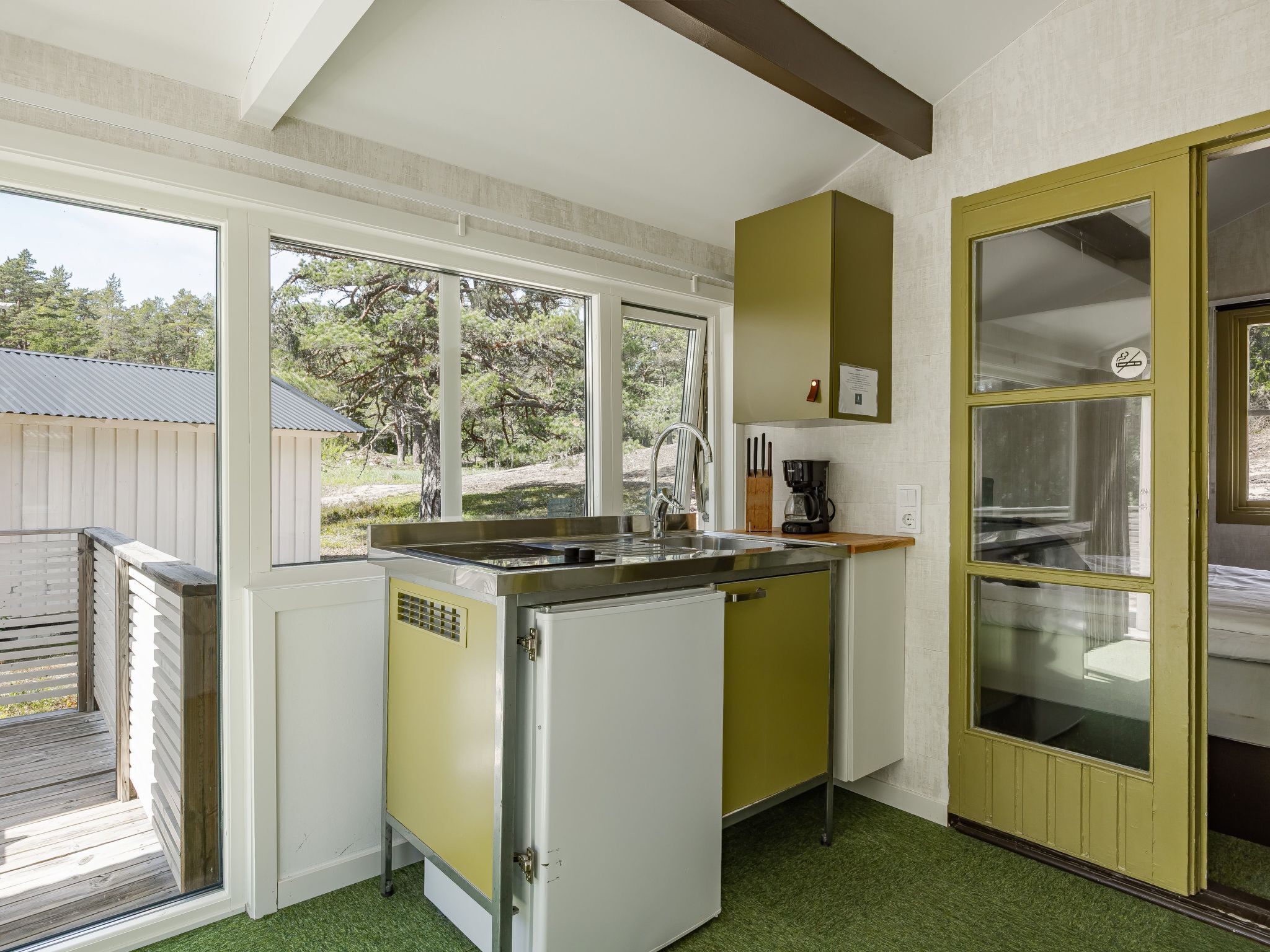 A compact kitchen with a sink, a coffee maker, and a window overlooking a wooded area.