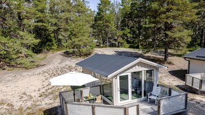 Une petite cabane à un seul étage, dotée d’une terrasse et d’un patio couvert.