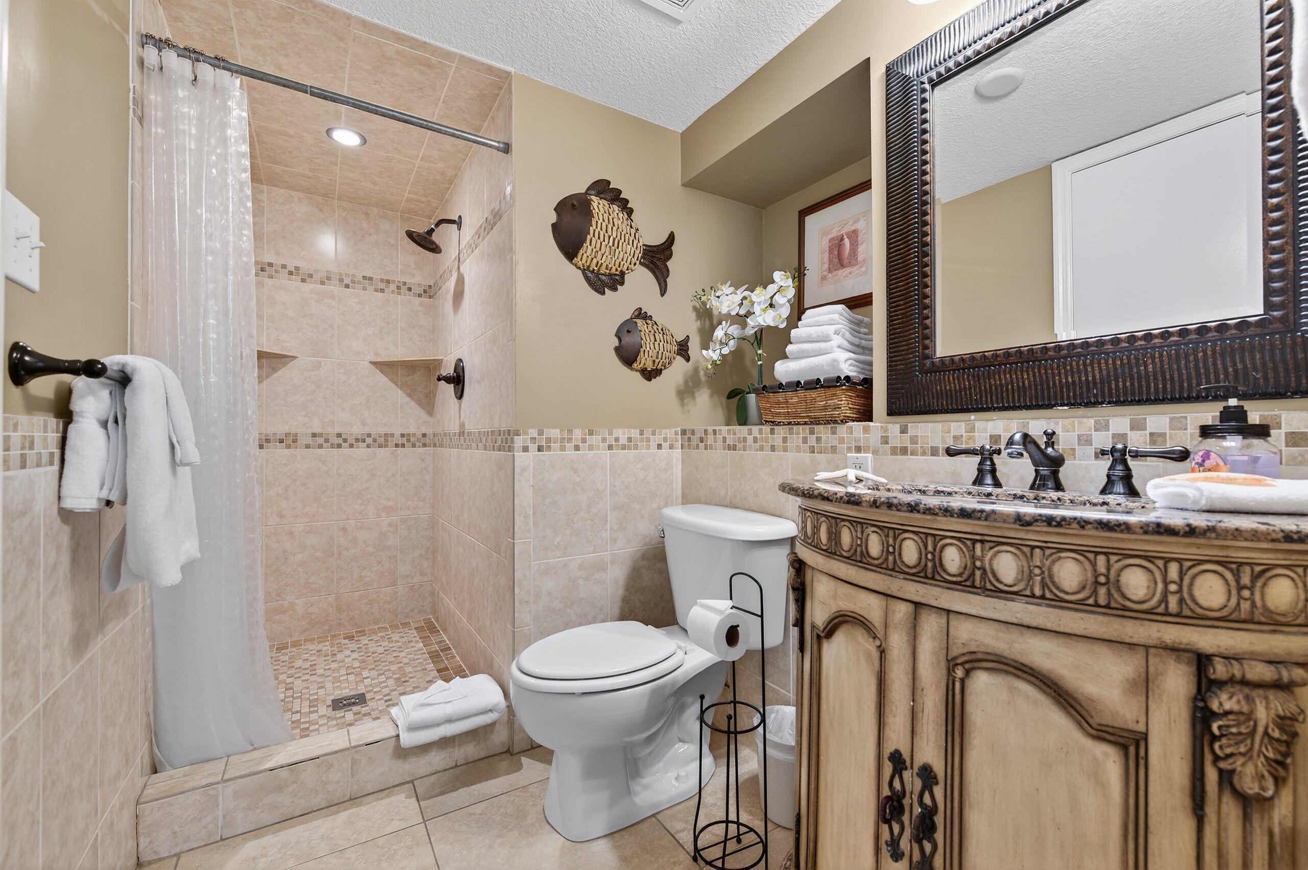 A bathroom with a shower, toilet, and vanity with a mirror.