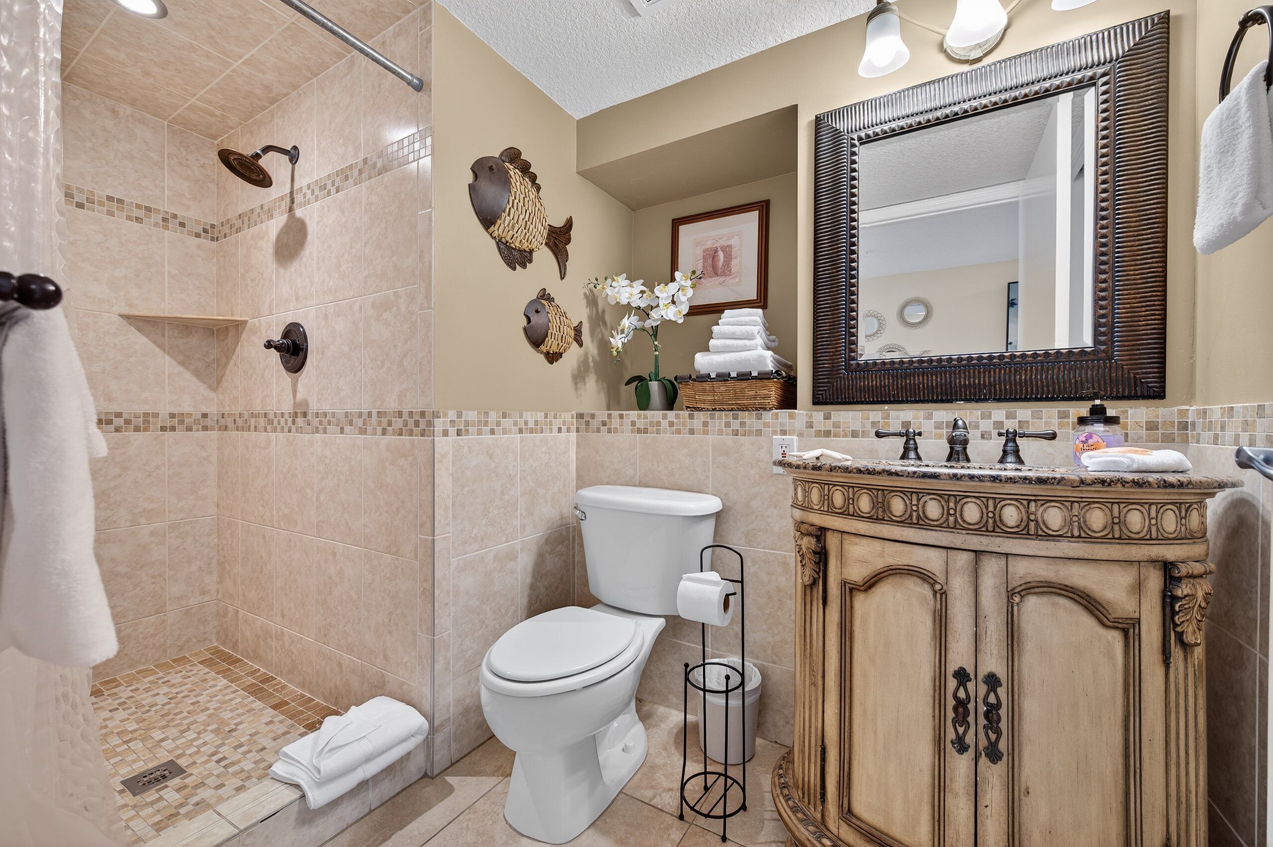 Une salle de bain équipée d’une douche, de toilettes, d’un meuble-lavabo et d’un grand miroir.