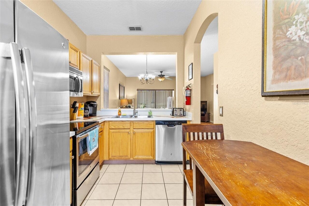 A kitchen with stainless steel appliances, wooden cabinets, a dishwasher, and a dining area with a wooden table.