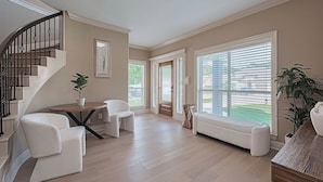 A spacious living room with a curved staircase, a round wooden table, and a built-in bench. - "Fitz-Just-Right" home in Walden: Boat ramp, Pickleball, Community Pools! (Montgomery)