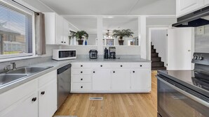 A modern kitchen with white cabinetry, a built-in microwave, a coffee maker, and a stainless steel oven.