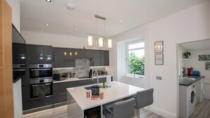A modern kitchen with stainless steel appliances, a central island, and a view of the outdoors. - Penthouse at the White House near Edinburgh (Bathgate)