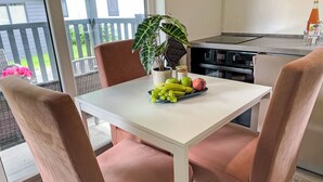 A dining area with a white table, two cushioned chairs, a potted plant, and a fruit bowl. - Vacation home Joschi by Interhome (Plau am See)