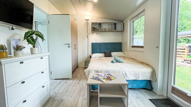 A modern bedroom with a bed, bedside table, and a large window. - Vacation home Joschi by Interhome (Plau am See)