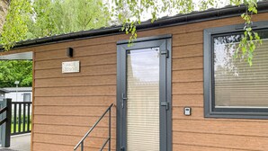 A modern building with a wooden exterior, a door with a window, and a small outdoor area with steps. - Vacation home Joschi by Interhome (Plau am See)