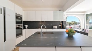Una cocina moderna con armarios blancos, una encimera negra y un amplio ventanal con vistas.
