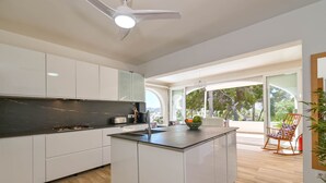 Una cocina moderna con armarios blancos, encimera negra y una isla central.