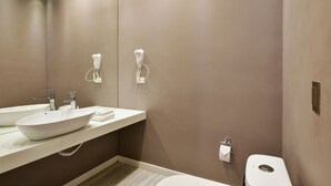 Ein modernes Badezimmer mit einem großen Spiegel, zwei Waschbecken, einer Toilette und einem Handtuchhalter.