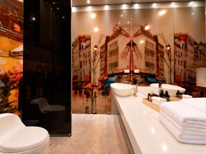 A modern bathroom with a large mirror, a white sink, and a black chair.