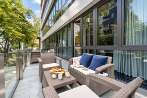 Un área de estar exterior moderna con mobiliario de mimbre, una bandeja de frutas y vistas al exterior del edificio.