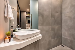 Un baño moderno con un lavamanos grande de color blanco, un espejo y una zona de ducha.