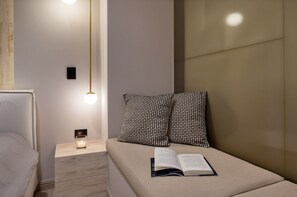 Ein ordentlich eingerichtetes Schlafzimmer mit einem Bett, Nachttischlampen, einem Nachttisch mit Kerze und Buch.