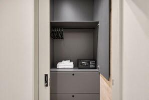 Ein grauer Kleiderschrank mit einem schwarzen Safe, einer Kleiderstange und einer Schublade.