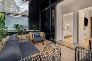 Ein modernes Zimmer mit einer Couch, Sesseln, einem kleinen Tisch und einem Bett.