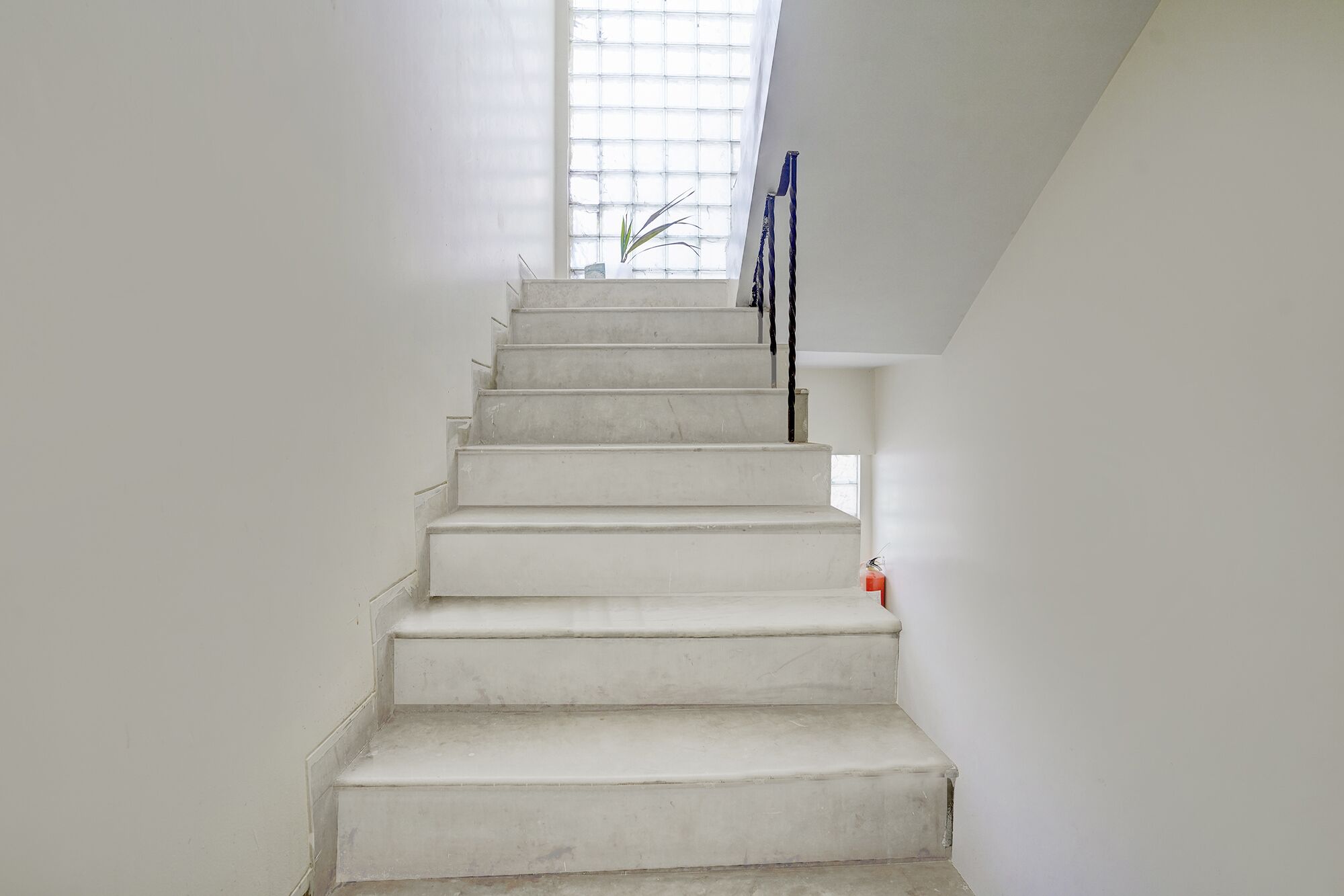 A white staircase with a handrail, leading up to a window with a view of the outside.