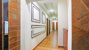 A hallway with patterned walls, a wooden floor, and a door at the end. - FabHotel Emerald Suites - Near MG Road Metro Station (Bangalore)
