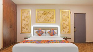 A hotel room with a large bed, a wardrobe, a desk, and a door. - FabHotel Emerald Suites - Near MG Road Metro Station (Bangalore)