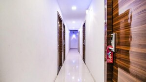A corridor with a polished floor, wooden doors, and a digital lock on one door. - Fabexpress Konak (Mumbai)