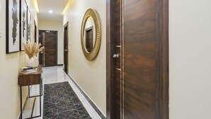 Un pasillo con obras de arte enmarcadas, un espejo y una puerta.