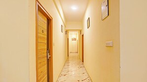 A hotel hallway with wooden doors, marble flooring, and framed pictures on the walls. - FabHotel Kings Palace Manyata - Near Manyata Tech Park Main Gate (Bangalore)